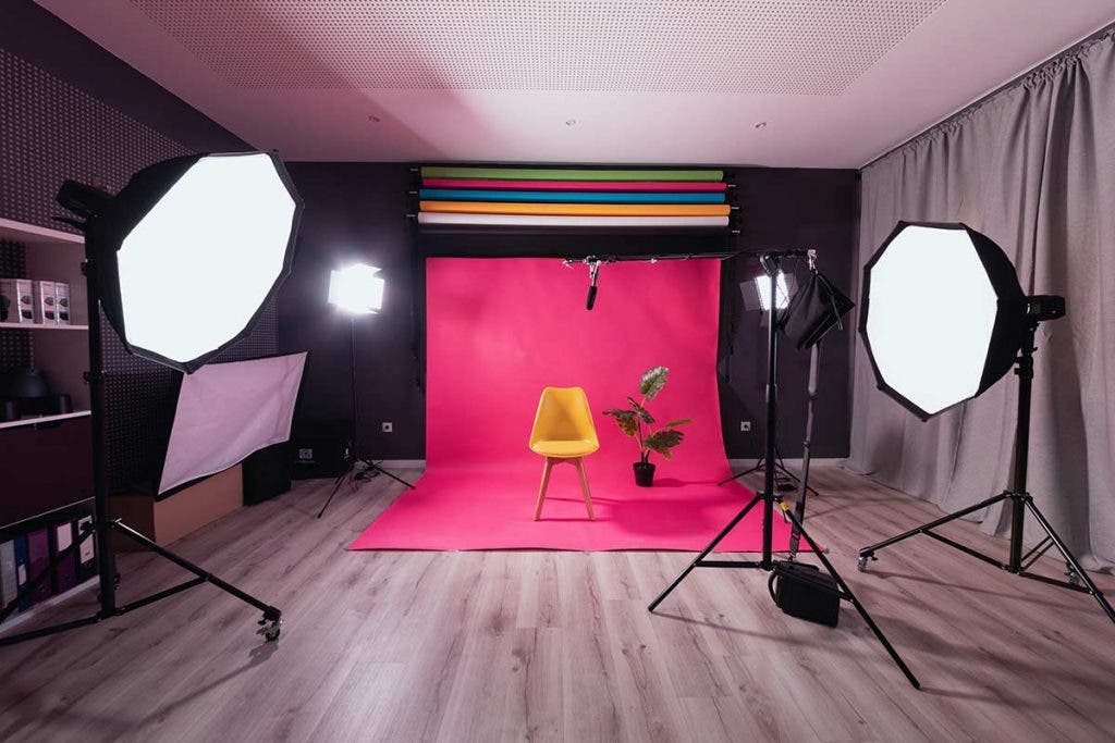 photo studio with pink backdrop, chairs, and softbox bank lighting