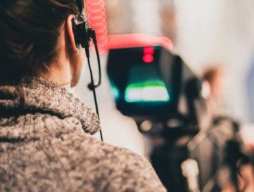 documentary filmmaker recording footage and audio with camera and headphones
