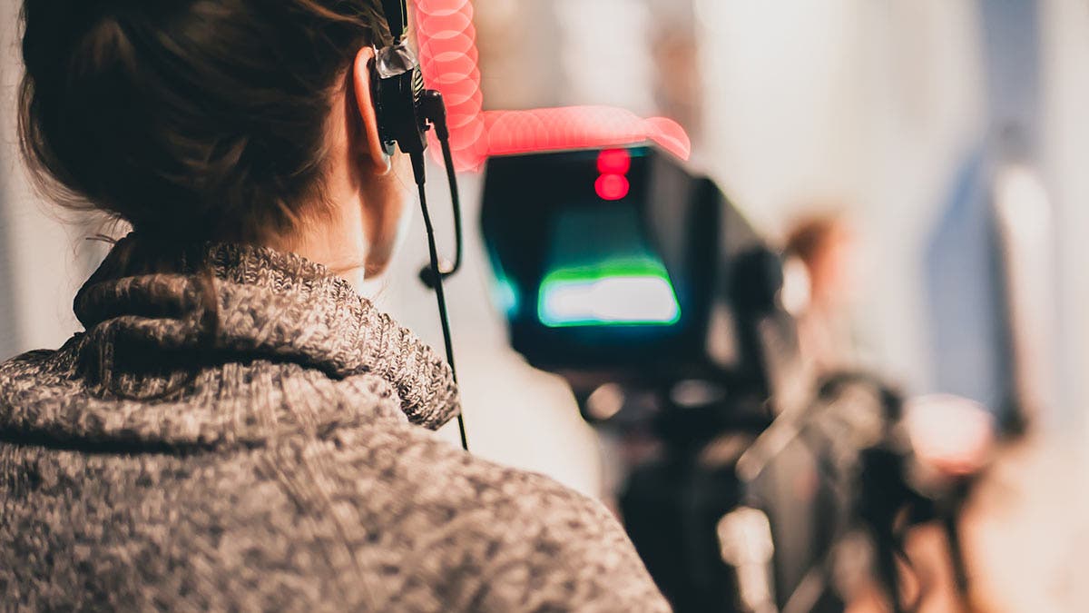 documentary filmmaker recording footage and audio with camera and headphones