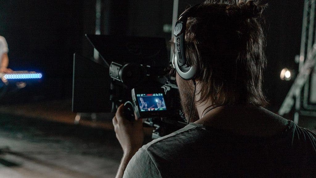 documentary filmmaker recording footage and audio with camera and headphones