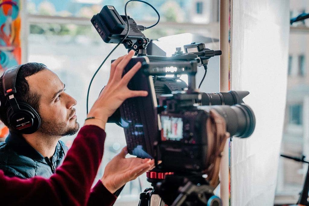 documentary filmmaker recording footage and audio with camera and headphones