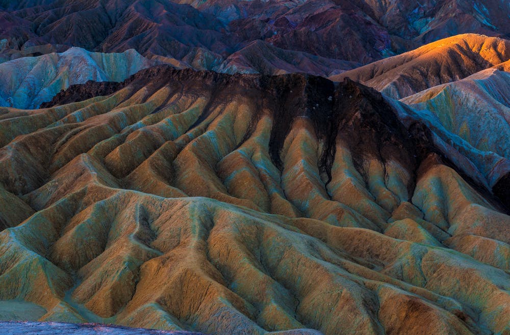 I was at Zabriskie Point in Death Valley at sunrise but there were clouds in the sky that cast a shadow over some of the eroded badland formations the area is known for. By eliminating the sky completely, I was able to put them in the perfect light to show their shapes and subtle colors. Shot at 60mm with my 24-70mm zoom lens at f/30 for sharpness.