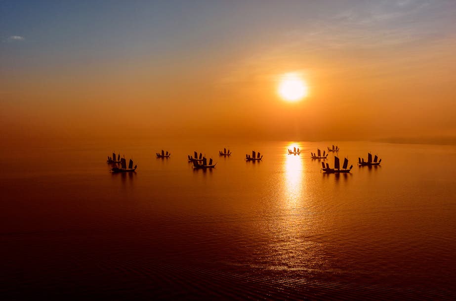Chinese junks scattered across Lake Taihu in the Zhejiang Province. I was in Huzhou for a commercial shoot, but made sure I had an extra day in the schedule to explore the region afterwards. I was up early wanting to catch the sunrise out over the lake, and was thrilled to see this flotilla of junks sitting serenely and providing the ideal photo opportunity. The low lying atmospheric fog/smog helped disburse the sun’s light and added a golden glow to my image.