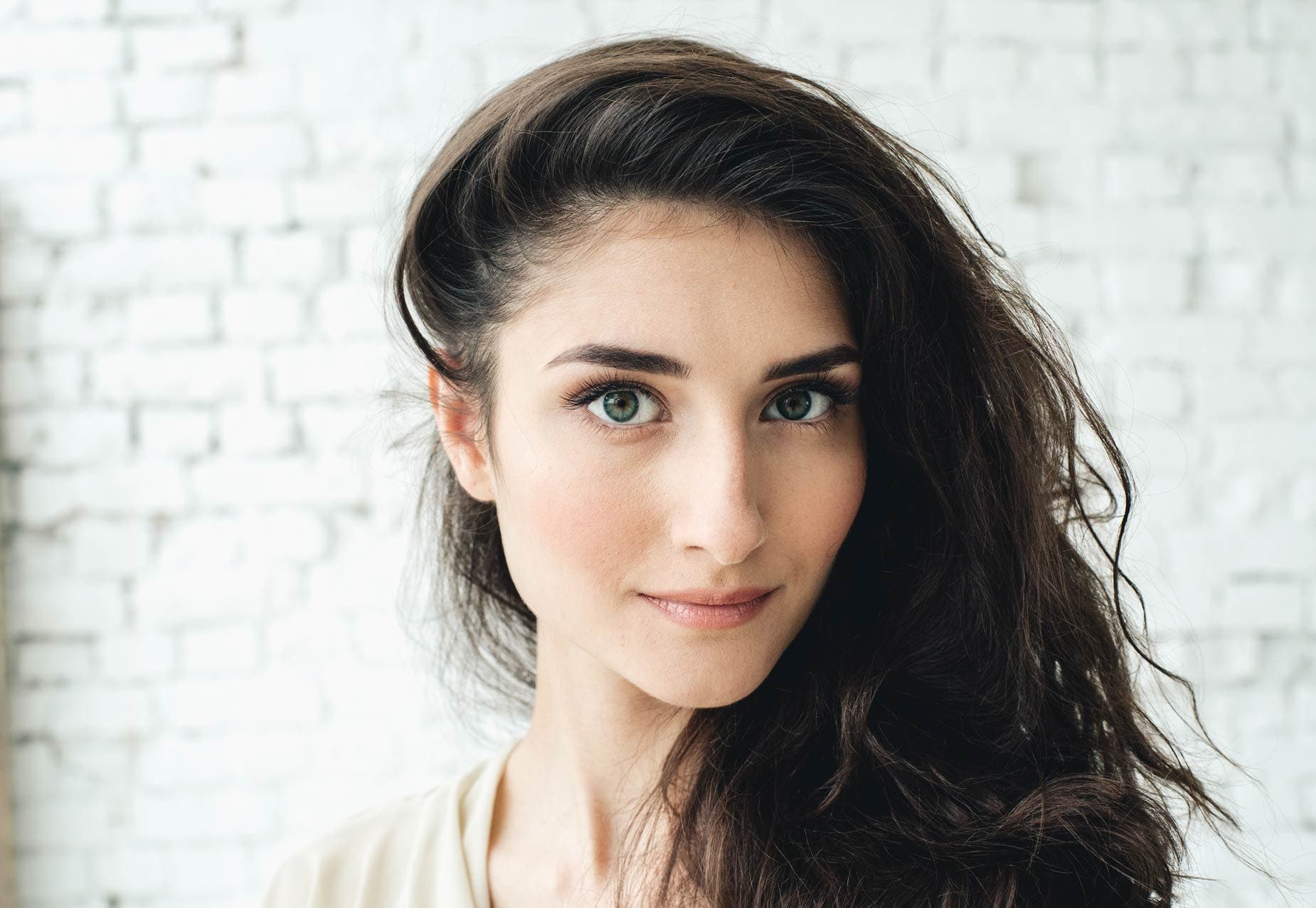 alt text="portrait of a woman in front of a white brick wall"