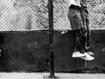 child watching his playmates street photography
