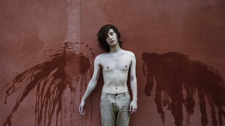 pale model standing in front of a red wall