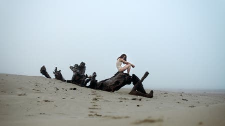 model sitting on deadwood