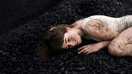dirty female model lying on coal