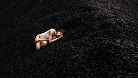 dirty female model lying on coal
