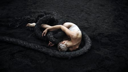 naked model lying in the sand with thick ropes