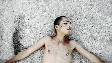 male model lying in the sand
