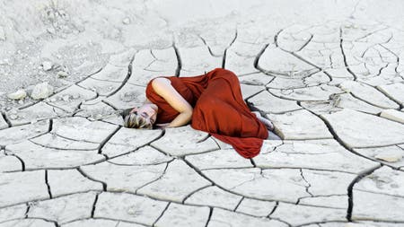 model in red dress on cracked soil