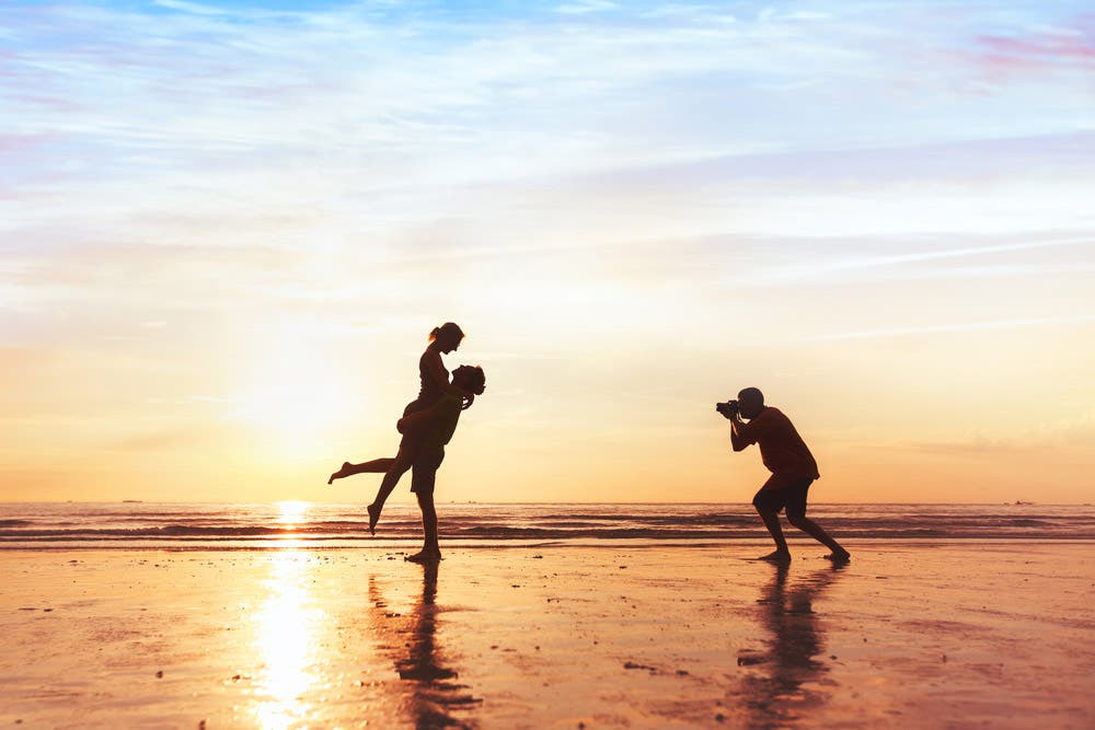 Photographer capturing a couple’s day at the beach at sunset