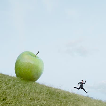 green apple rolling down hill chasing running man