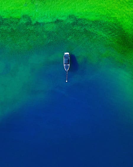 boat in green and blue water drone photography