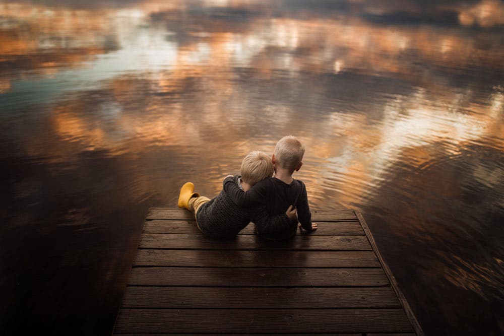 two young boys sitting on a dock