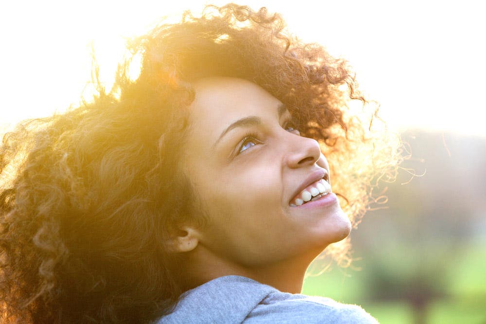 Profile shot and close-up portrait of woman looking up at the sky and smiling