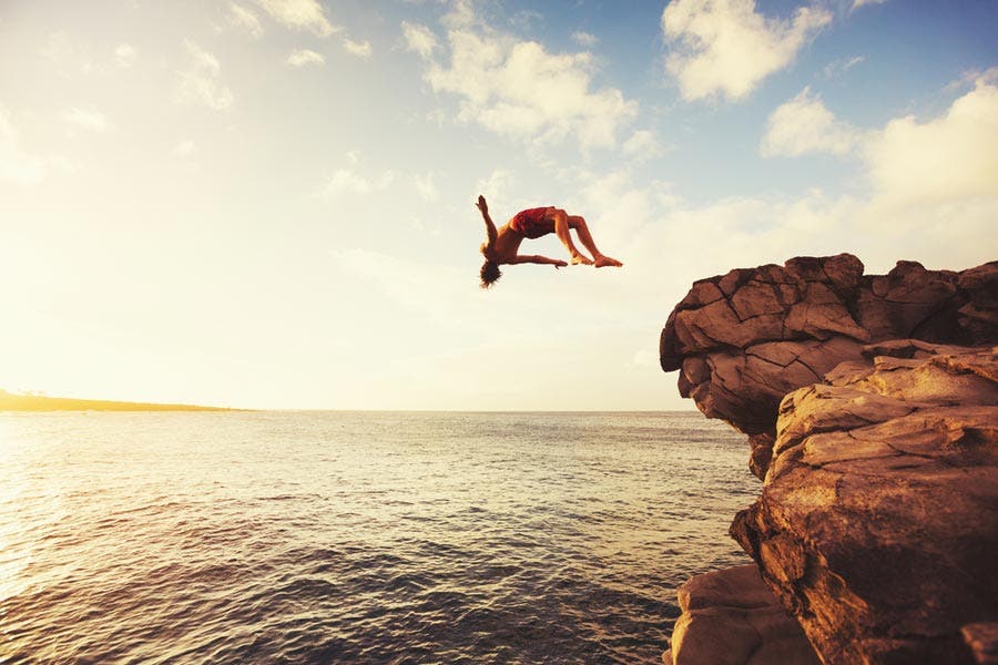 Man doing a backflip off a cliff into the ocean