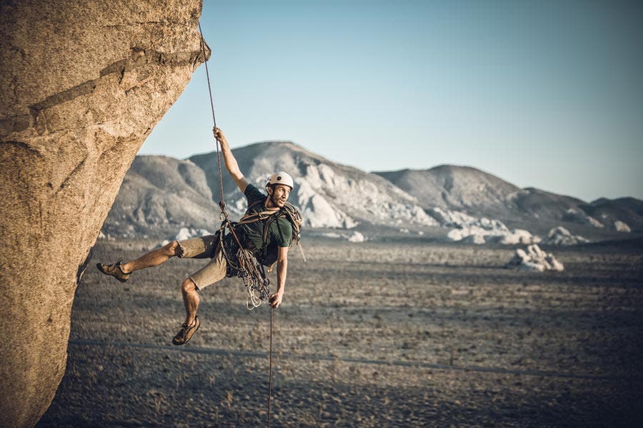 Man rappelling down a rocky mountain