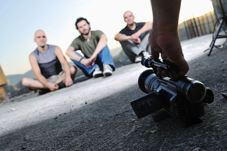 three men sitting on the ground shooting music video