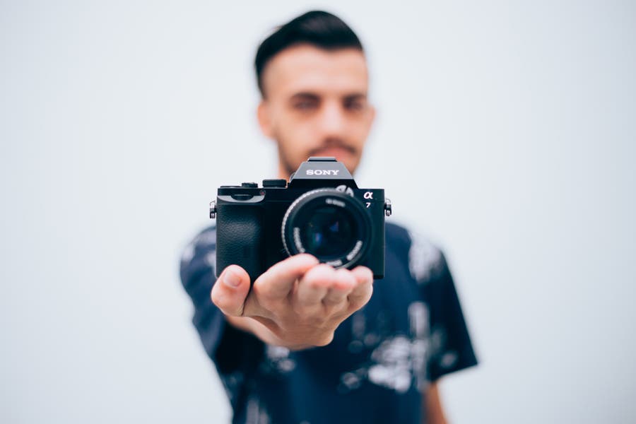 A man holding out a mirrorless camera on his palms