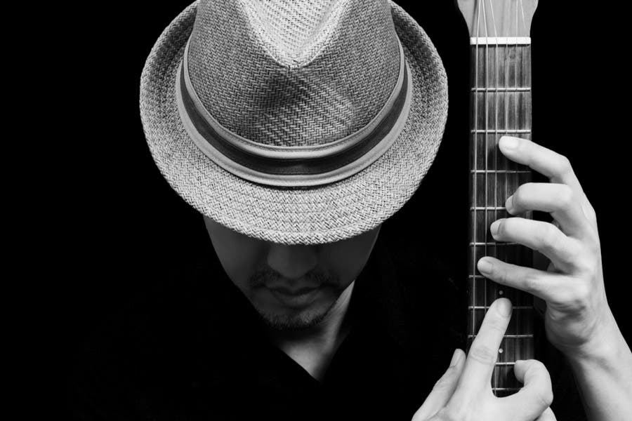 Faceless portrait of man looking down and playing the guitar