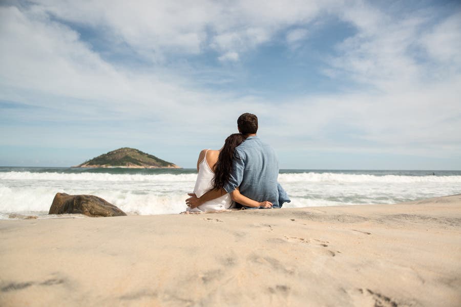 Faceless portrait of couple sitting together at the beach