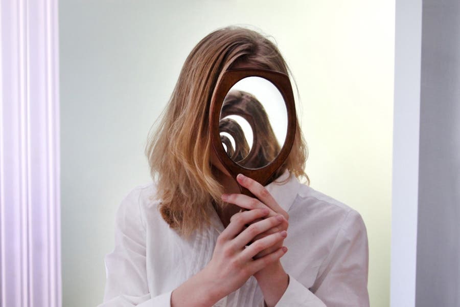 Faceless portrait of a woman holding a wooden hand mirror