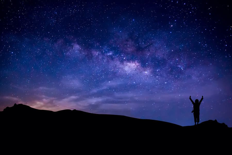 Silhouette of landscape and person against starry night sky