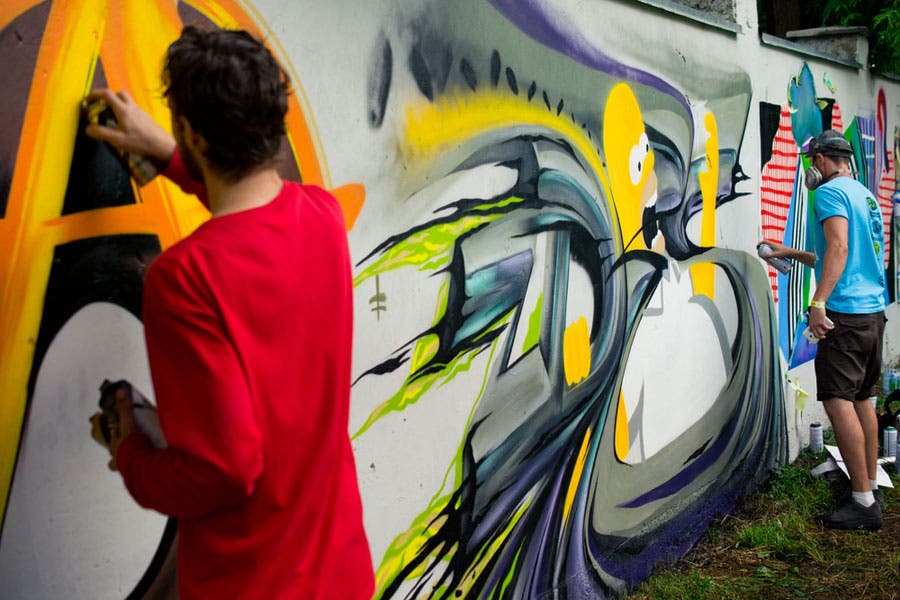 Artists spray painting graffiti on wall