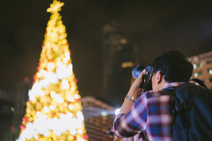 man taking picture of christmas tree