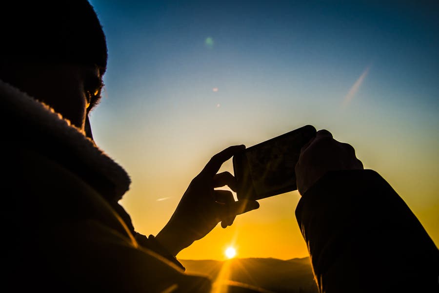 man taking a photo outdoors during sunset
