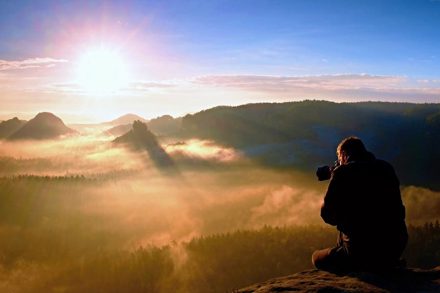Cinematographer video recording sunset from high mountain