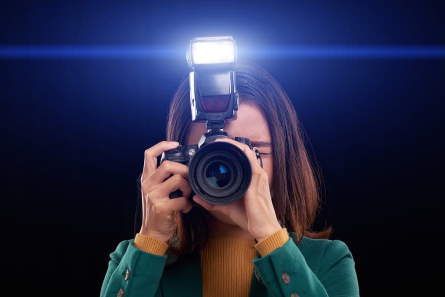 Female photographer aiming camera and flash