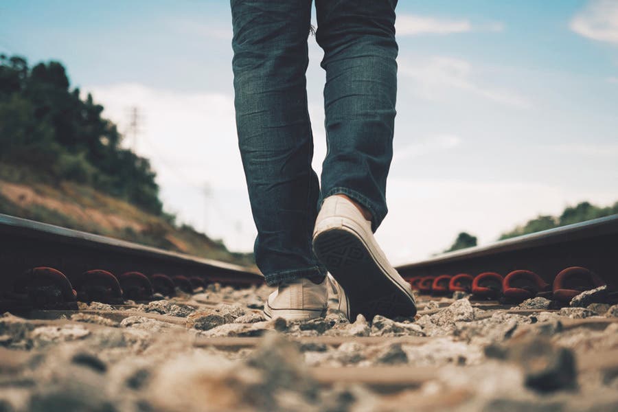 Cinematic shot of person walking in the middle of train track