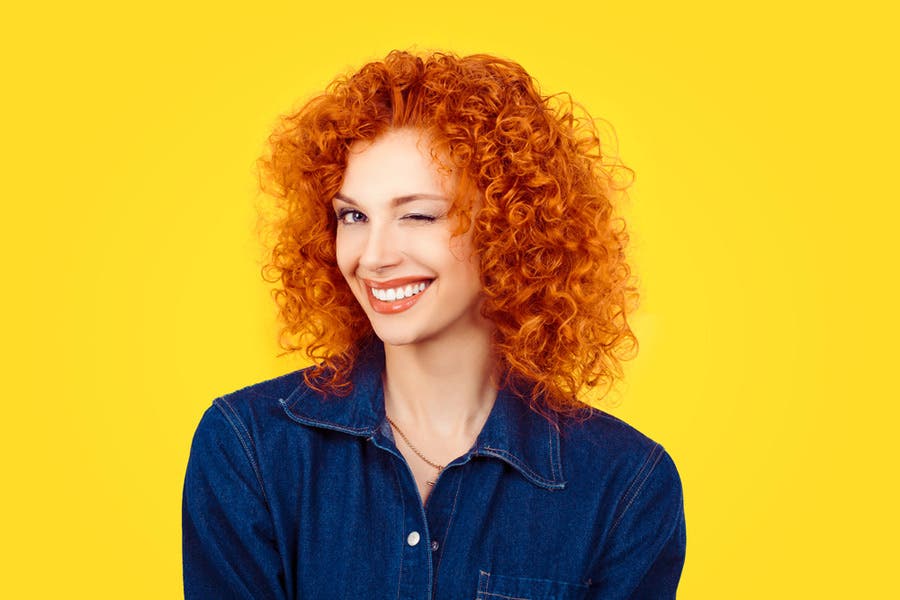 Cheerful photo of woman with orange hair against yellow background