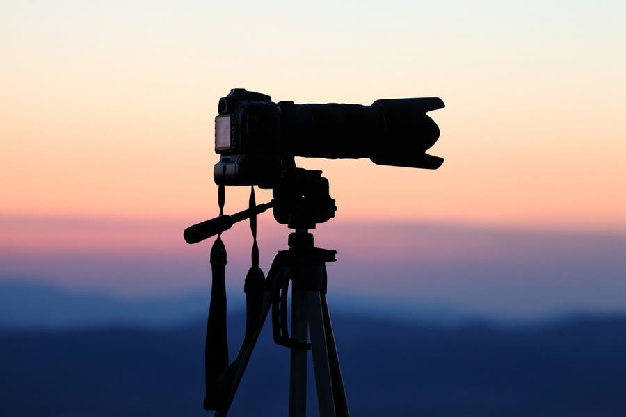 Silhouette of camera on tripod against the horizon at sunset - Basic Camera Movements