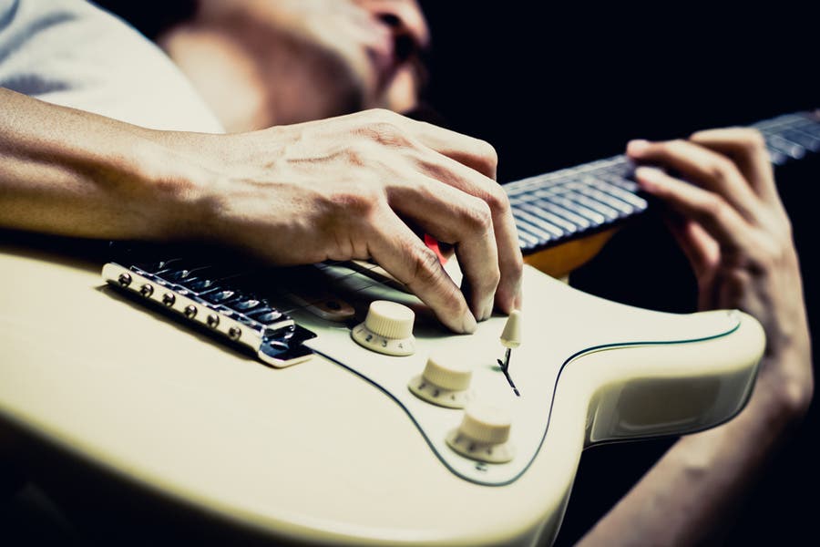 Man playing white stratocaster guitar shot below