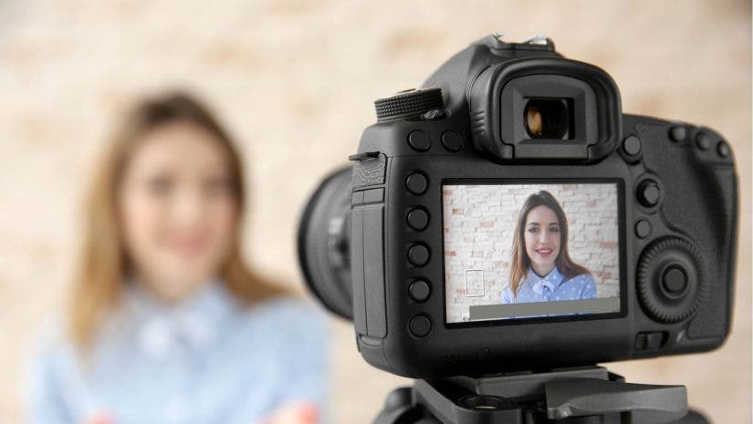 DSLR camera focusing on smiling woman who is blurred in the background