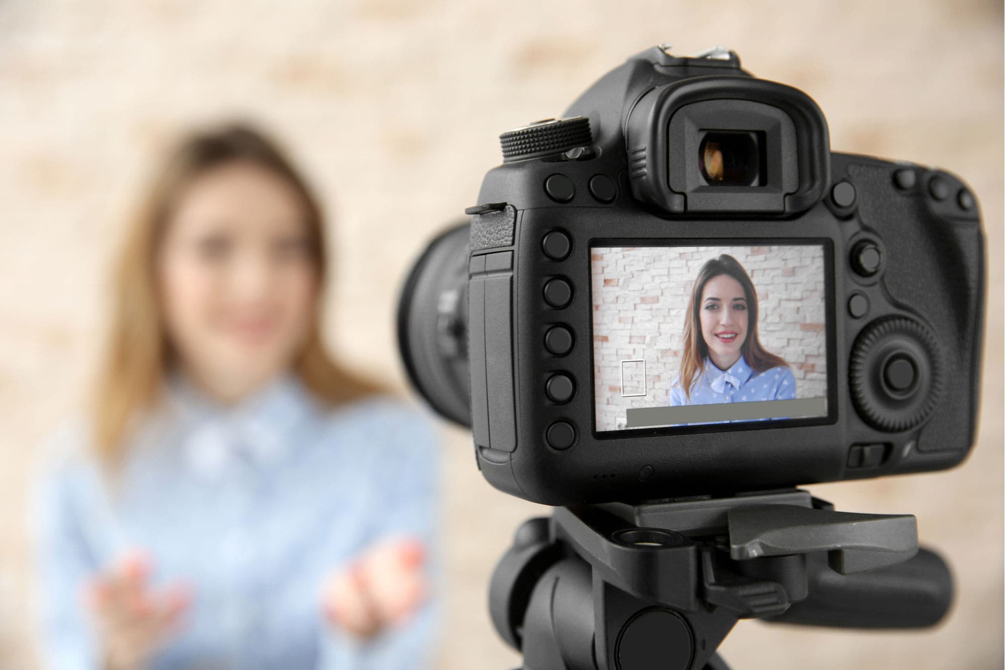 DSLR camera focusing on smiling woman who is blurred in the background