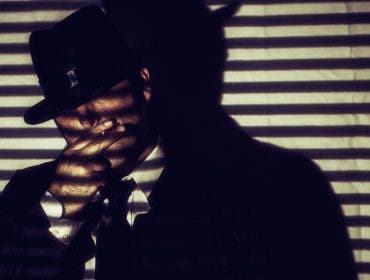 Man smoking behind shadows of blinds
