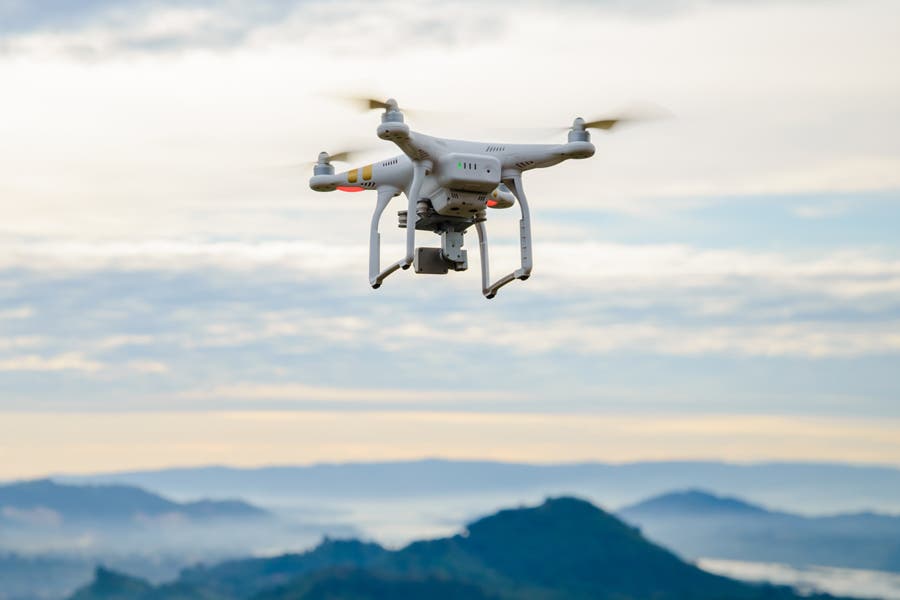 Drone DJI Phantom 3 flying over mountains in cloudy horizon