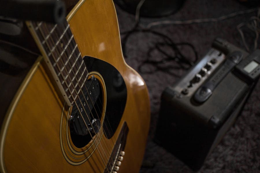 Close-up of an acoustic guitar with an acoustic guitar amp in the background