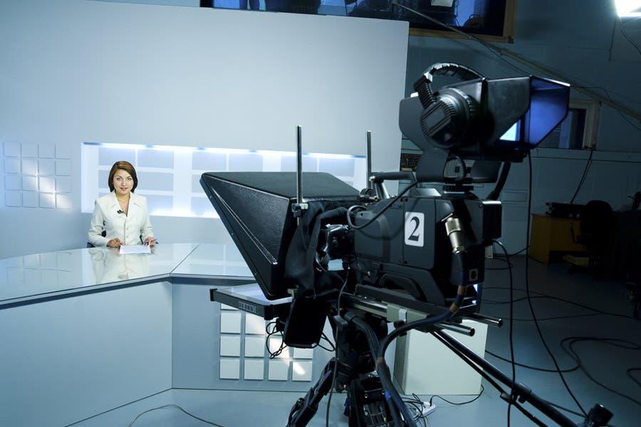 A female announcer reads off a teleprompter