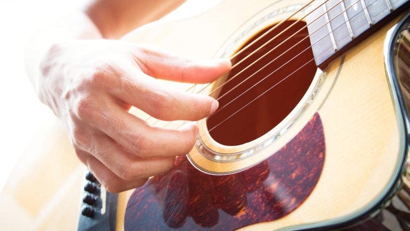 Man plucking strings on acoustic guitar
