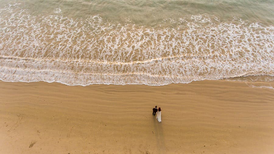 aerial shot of wedded couple by the shore