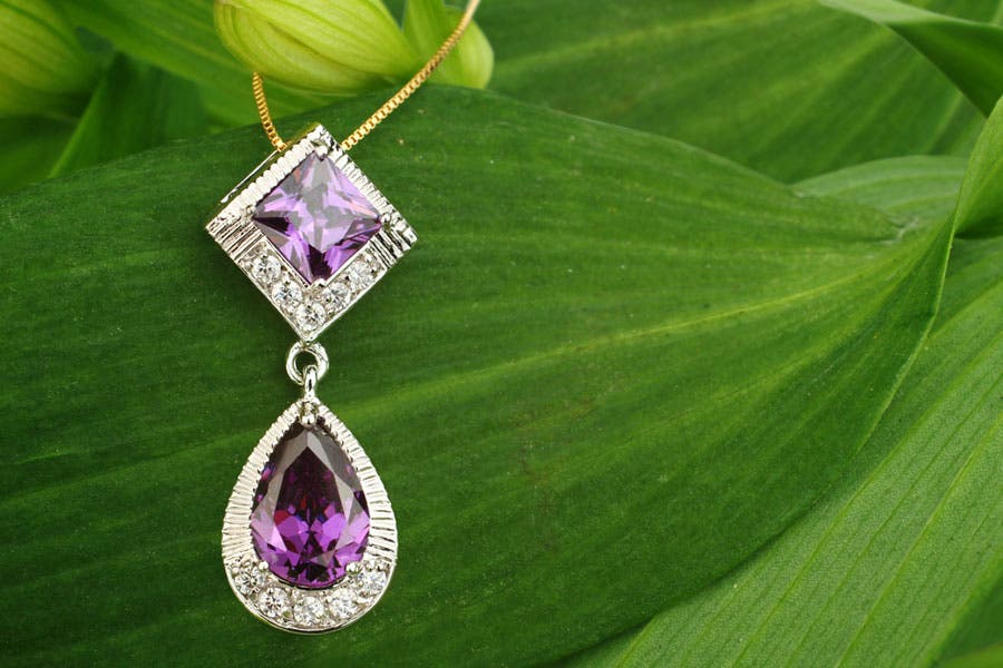 Purple gemstone necklace with big green leaf background