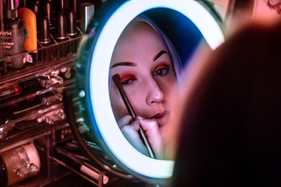 a ring light brightens up a girl’s face while she applies eyeshadow