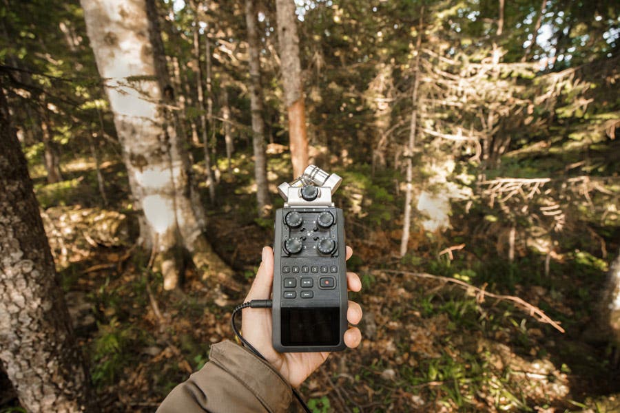 man holding a bulky audio recorder in the forest