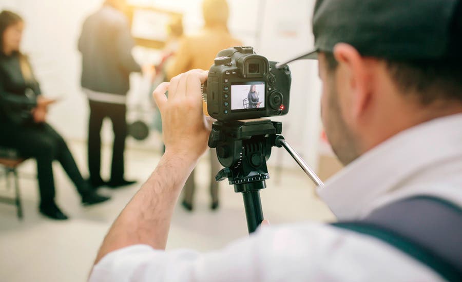 man carefully adjusting lens while recording with tripod videography